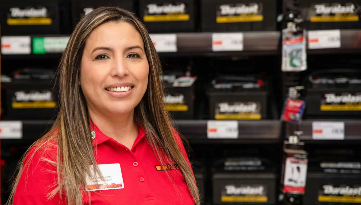 AutoZone employee in front of Duralast battery wall